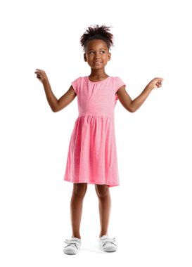 Pembe elbiseli küçük Afro-Amerikalı kız beyaz arka plandaki bir şeyi işaret ediyor.