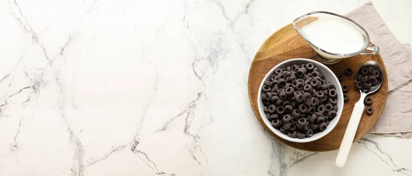 Composition with tasty cereal rings and milk on light background with space for text