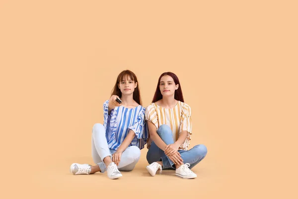 Teenage Twin Sisters Remote Control Sitting Beige Background — Stock Photo, Image