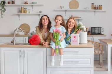 Genç kadın, küçük kızı ve annesi evde Uluslararası Kadınlar Günü 'nde çiçeklerle birlikte.