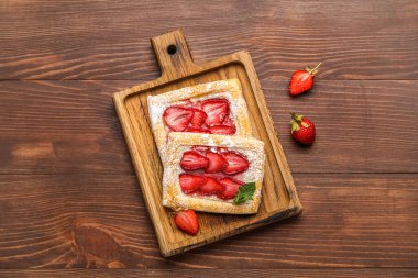 Ahşap zemin üzerinde lezzetli çilekli börek olan tahta.