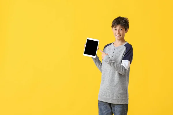 Teenage boy pointing at tablet computer on yellow background