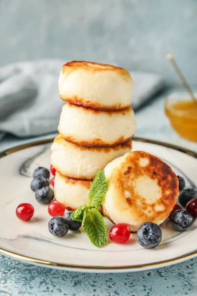 Plate with stack of cottage cheese pancakes and berries on blue background