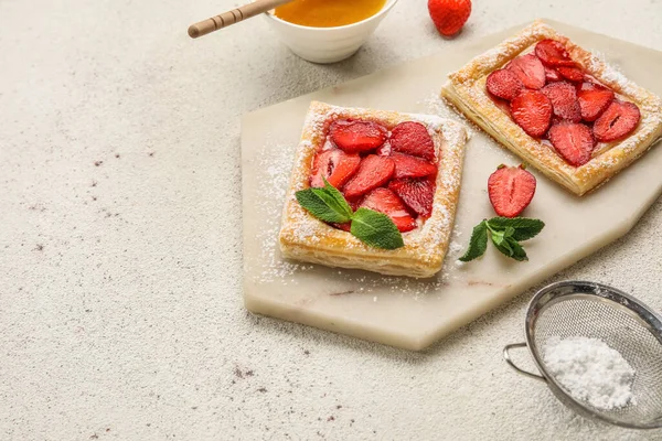 Board with sugar powdered puff pastry and strawberry on light table