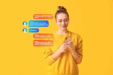 Cep telefonlu genç bir kadın sarı arka planda internette sohbet ediyor.