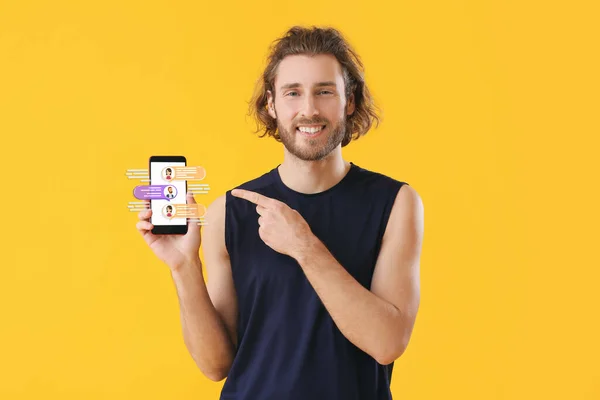 Happy man with mobile phone chatting online on yellow background