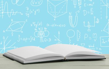 Masada mavi arkaplanda çizimler ve formüllerle birlikte açık bir kitap var. Kesin bilimler üzerine çalışıyorum.