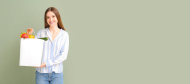 Yeşil arka planda yiyecek dolu kese kağıdıyla genç bir kadın ve mesaj için yeri var.