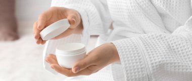 El kremi kavanozuyla güzel genç bir kadın, yakın plan.