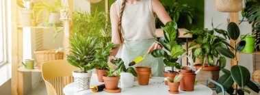 Evde çiçekleriyle ilgilenen genç bir kadın.