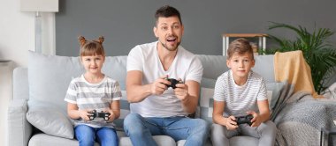 Father and his little children playing video games at home