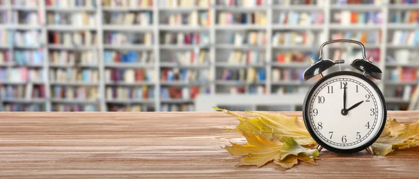 Ξυπνητήρι Και Φθινοπωρινά Φύλλα Στο Τραπέζι Στη Βιβλιοθήκη — Φωτογραφία Αρχείου