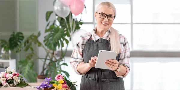 お店でタブレットコンピュータと熟女の花屋 — ストック写真