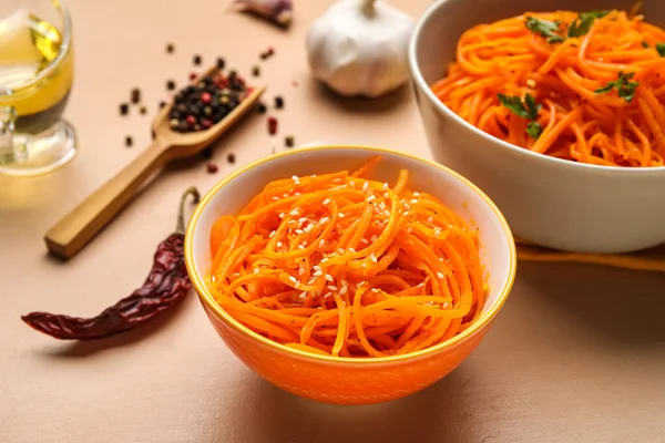 Bowls of korean carrot salad on color background