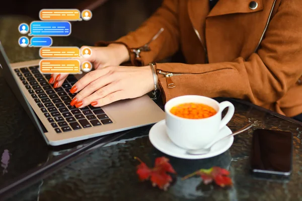 Woman with laptop chatting online at table in cafe