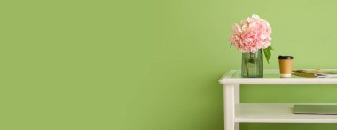 Ortanca çiçekli vazo ve yeşil duvarın yanındaki masada bir fincan kahve.