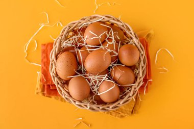 Arka planda kahverengi tavuk yumurtaları olan hasır sepet.