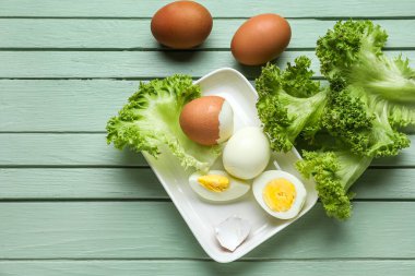 Haşlanmış tavuk yumurtası ve ahşap renkli marullu tabak.