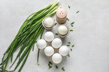 Tavuklu yumurta ve açık arkaplanda yeşil soğanlı tutucular.