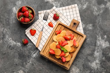 Ahşap pankek tahtası ve grunge arkaplanda çilekli kompozisyon