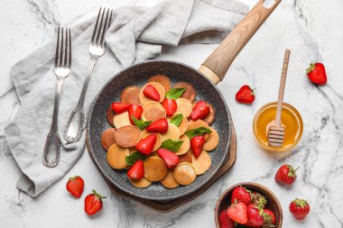 Lezzetli mini krepler, çilek ve açık arkaplanda bir kase bal içeren kompozisyon