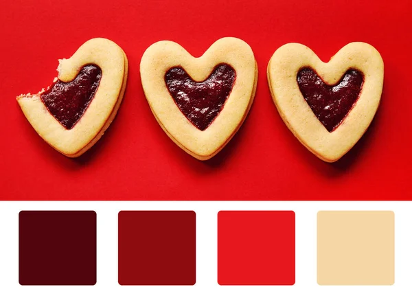 Tasty heart shaped cookies with jam on red background. Different color patterns