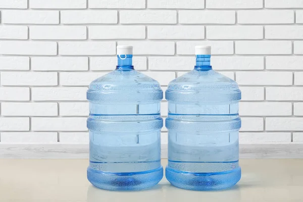 Bottles of clean water on floor near light brick wall
