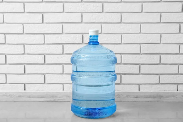 Bottle of clean water on floor near light brick wall