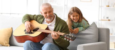 Büyük adam ve küçük torunu evde gitar çalıyorlar.
