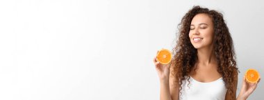 Açık arkaplanda portakalları olan güzel Afro-Amerikalı bir kadın.