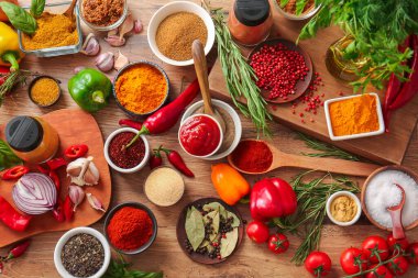 Ahşap arka planda çeşitli aromatik baharatlar, otlar ve sebzeler.