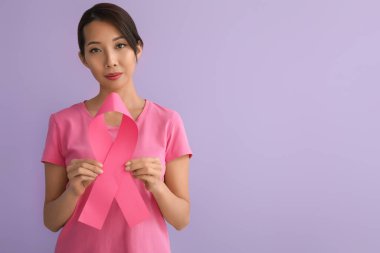 Leylak arka planında pembe kurdeleli genç Asyalı kadın. Göğüs kanseri farkındalığı konsepti