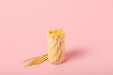 Pembe arka planda tahta kürdanlı bir kutu.