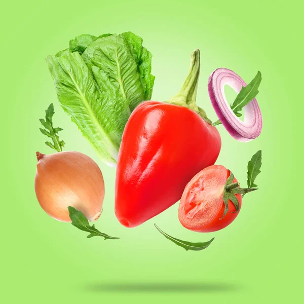 Flying fresh vegetables and herbs on green background