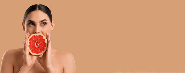 Naked young woman with fresh grapefruit on beige background with space for text