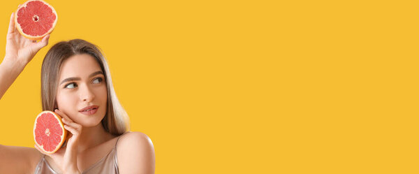 Beautiful young woman with grapefruit on yellow background with space for text