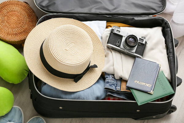 Opened suitcase with different clothes and traveler accessories