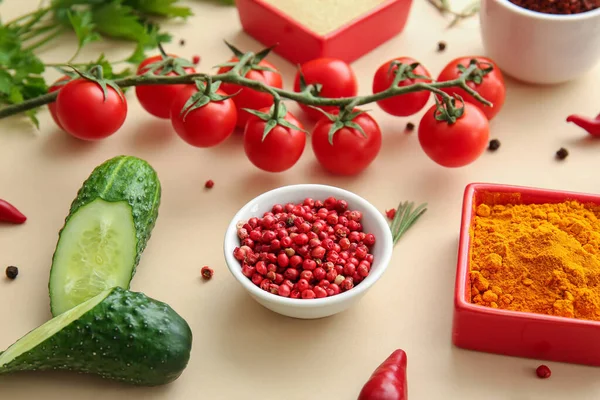 Bowls with spices and fresh vegetables on color background