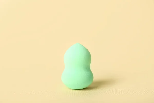 Green makeup sponge on color background