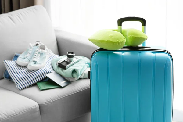 Suitcase and neck pillow near sofa in light room