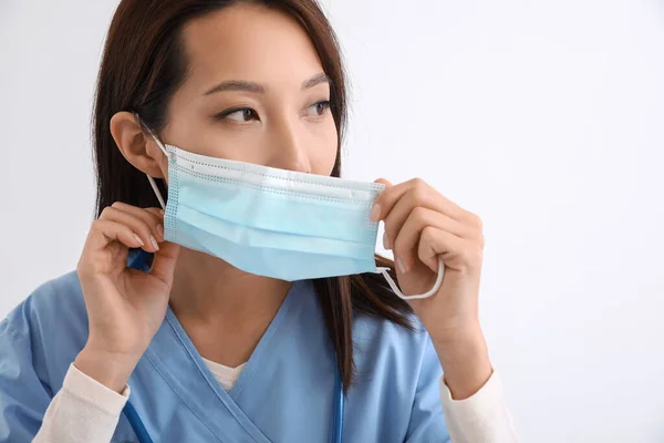 Female Asian Nurse Putting Medical Mask White Background — Stockfoto