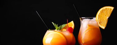 Glasses of tasty Tequila Sunrise cocktail on dark background with space for text