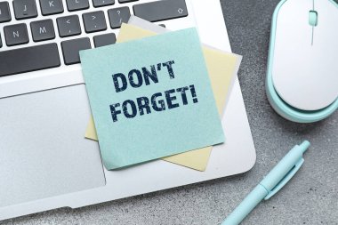 Dizüstü bilgisayar, yazılı kağıt. Gri arkaplanda kalemle birlikte unutma.