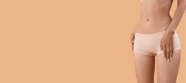 Slim young woman in underwear on beige background with space for text