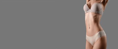 İç çamaşırlı, gri arka planda, mesaj için yeri olan zayıf genç bir kadın.