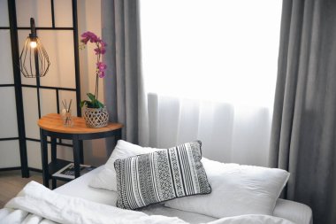 Çiçekli masa, sazlık ayırıcı ve şık yatak odasında parlayan lamba.