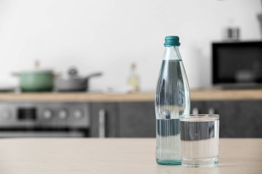 Mutfak masasında bir şişe ve bir bardak temiz su.