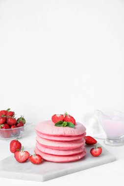 Lezzetli pembe krep ve açık arkaplanda çilekli pano.