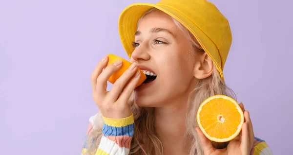 Beautiful Young Blonde Woman Eating Orange Lilac Background — Fotografia de Stock