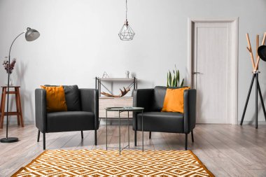 Modern oturma odasının içinde kahve masası olan siyah koltuklar.